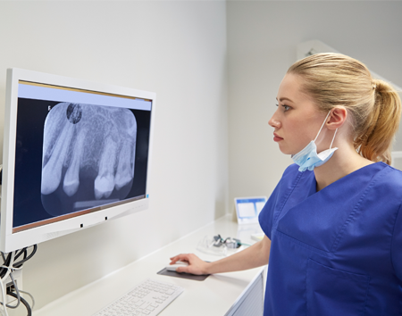 Dental Hygienist Looking at X-Rays for a Dental Bridge in Raleigh, NC 